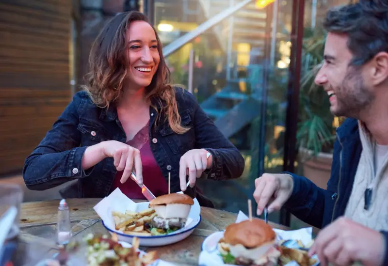 A happy couple using a restaurant voucher to get a discount on their meal.