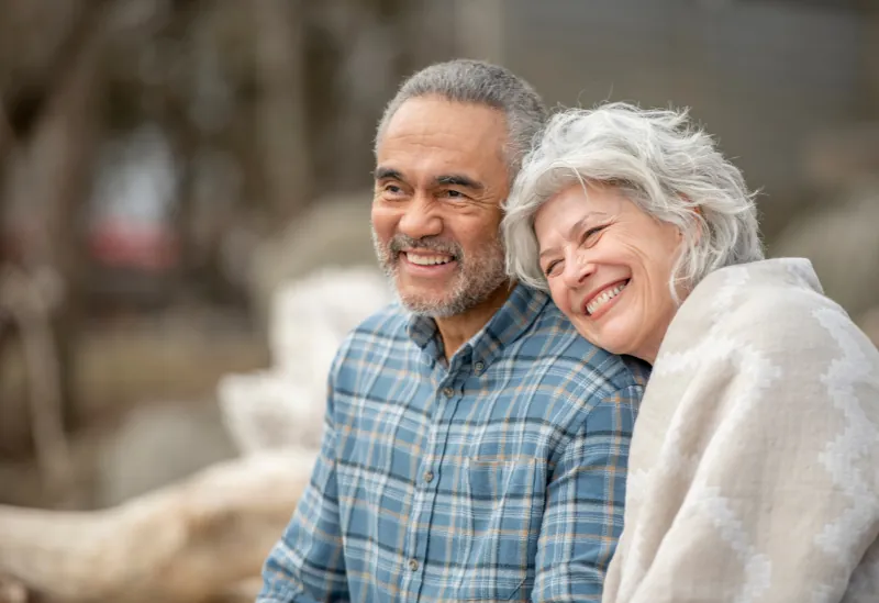 A retired couple enjoying affordable UK retirement housing with a scenic countryside view.
