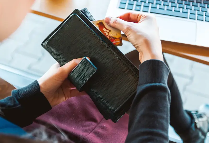 Woman taking a card from her purse while shopping online on a laptop