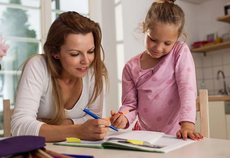 Mother and daughter planning family budget with notebooks and pens in kitchen