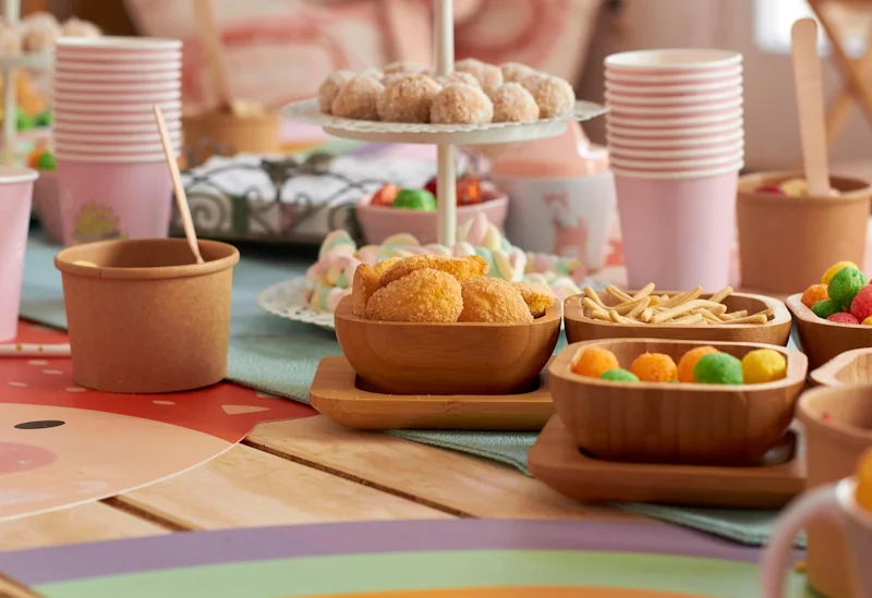 Bowls of crisps and party snacks with paper cups on a table