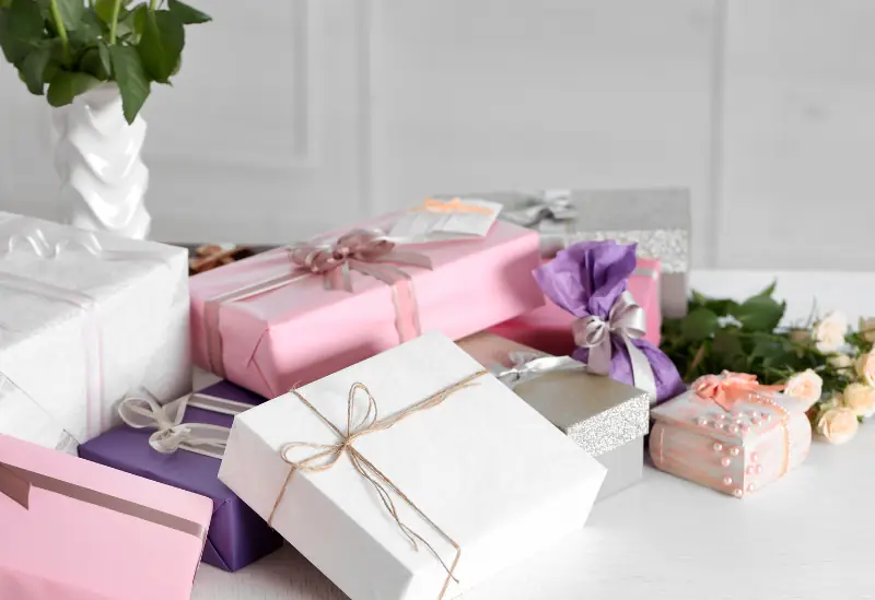 Wedding gift boxes on a table with roses, illustrating savings on gifts for wedding guests