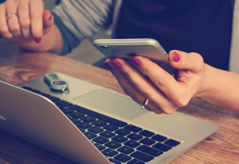 Person using laptop and phone to save money on everyday expenses with discounts.