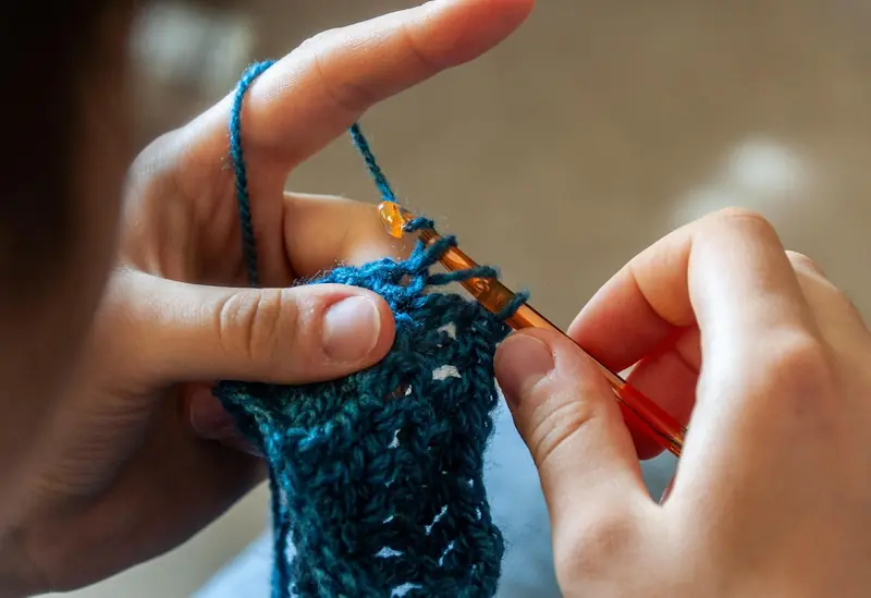 Close-up of hands crocheting, showcasing a budget-friendly and affordable hobby