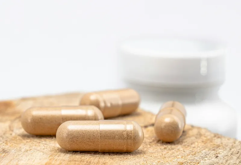 CBD capsules on a wooden surface with supplement bottle in background