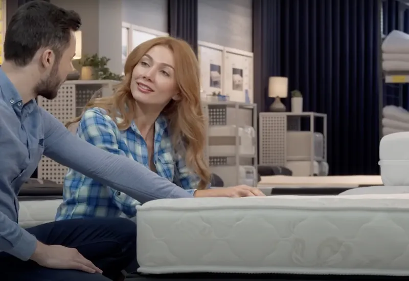 Couple discussing a purchase in a furniture store, using the Savzz cost per use calculator to decide if it's worth buying