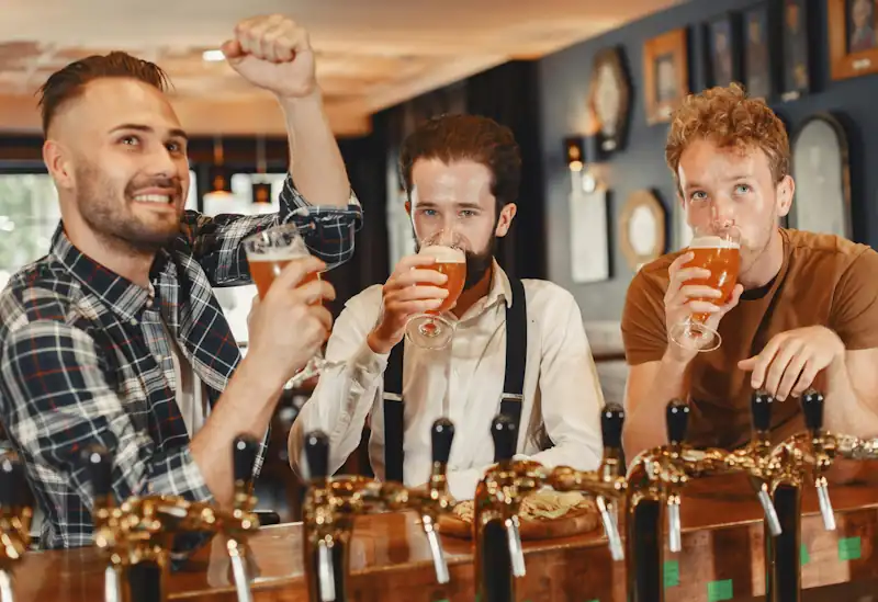 Friends enjoying drinks at a pub using the Savzz alcohol spending calculator to track how much they spend on alcohol each year