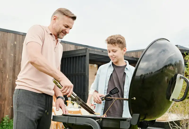 Family enjoying a BBQ in the garden using deals found on the Savzz outdoor cooking equipment page