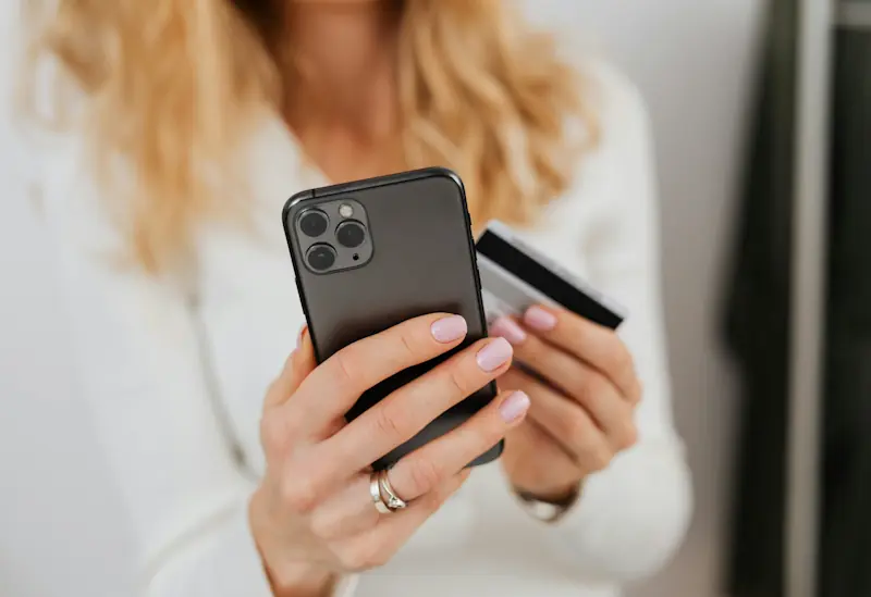 Person holding a phone and credit card while shopping online.