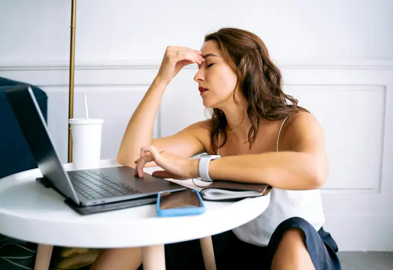Person looking tired while using a laptop at home.