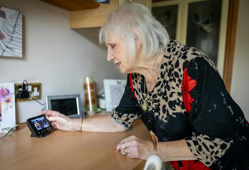 Elderly woman checking a smart meter at home using the Savzz energy appliance running cost calculator to manage her electricity bills