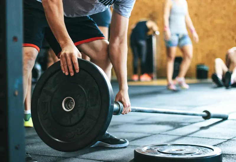 A person setting up for a barbell lift in a gym, illustrating typical UK gym membership costs.