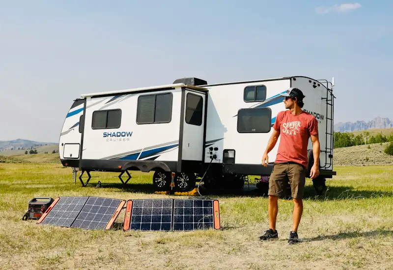 Campervan with solar panels charging a laptop and fridge, illustrating the Savzz solar savings calculator.