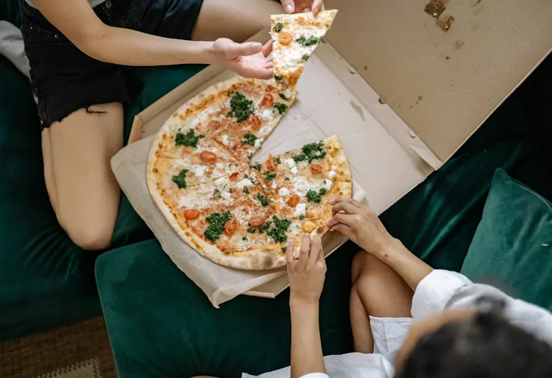 Two people sharing a takeaway pizza at home.