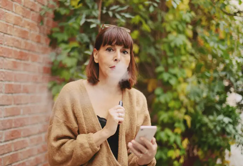 Person using a vape device with the Savzz vaping cost calculator showing their annual spend