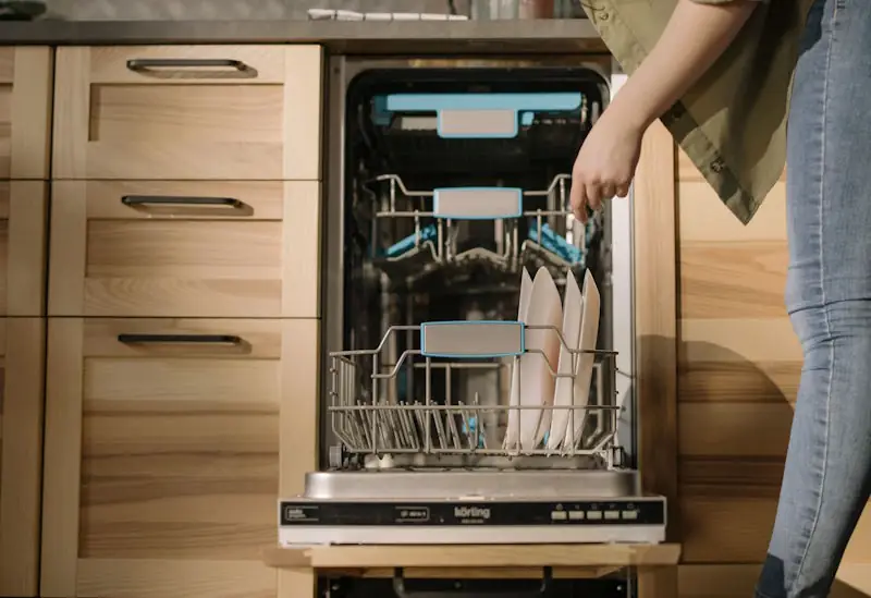 Person loading dishes into a dishwasher in a kitchen.