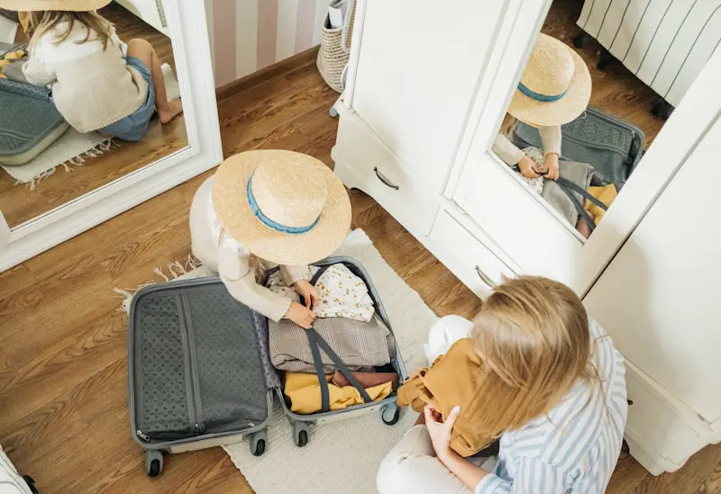 Two people packing a suitcase in a bedroom before a holiday trip.
