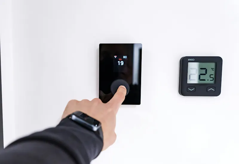 Person adjusting a home thermostat.