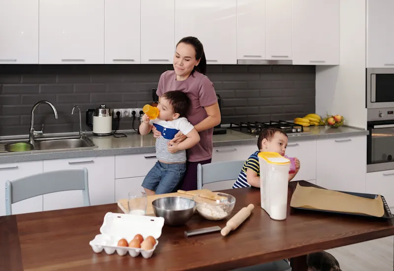 Parent baking in a busy kitchen while looking after children.