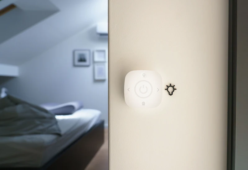 Smart home light switch on a wall in a modern bedroom.