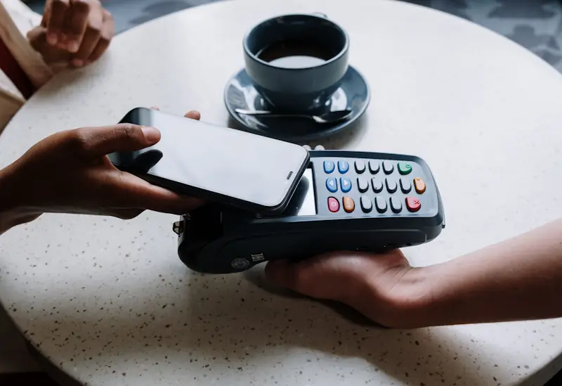 A smartphone being used to make a contactless payment at a café card terminal
