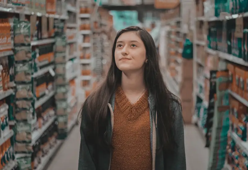 Someone looking at rows of items in a grocery store, appearing unsure what to choose