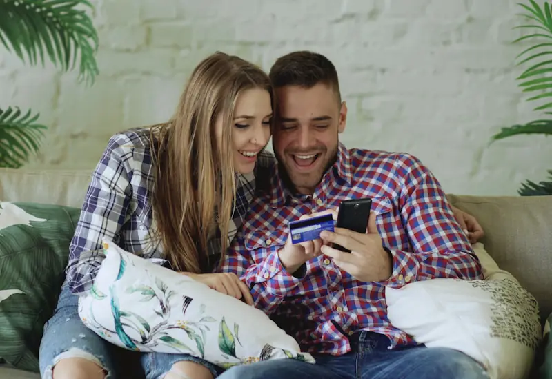 Two people smiling while checking loyalty points on a smartphone after a purchase.
