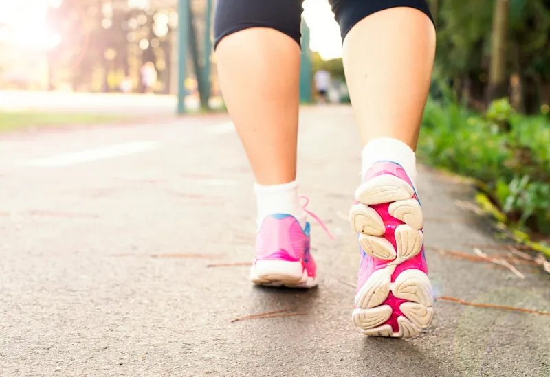 A person walking outdoors on a path wearing pink athletic shoes