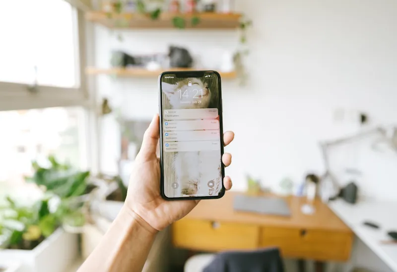 A person holding a phone showing several recent notifications