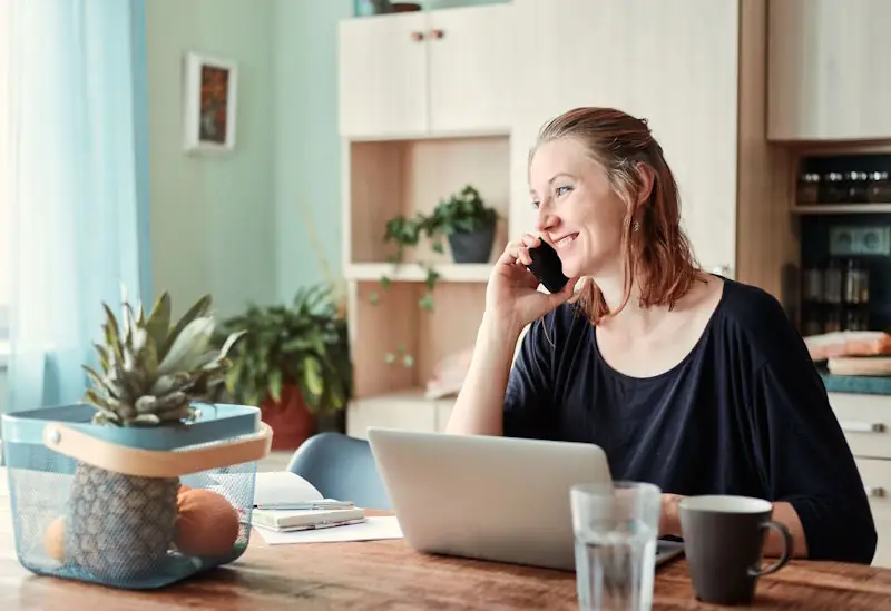 Person reviewing their monthly spending on a phone at a kitchen table, representing how to build a strong personal finance foundation in the UK.