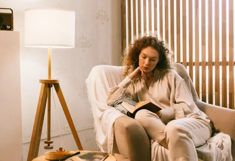 Person reading an open book in a softly lit room.