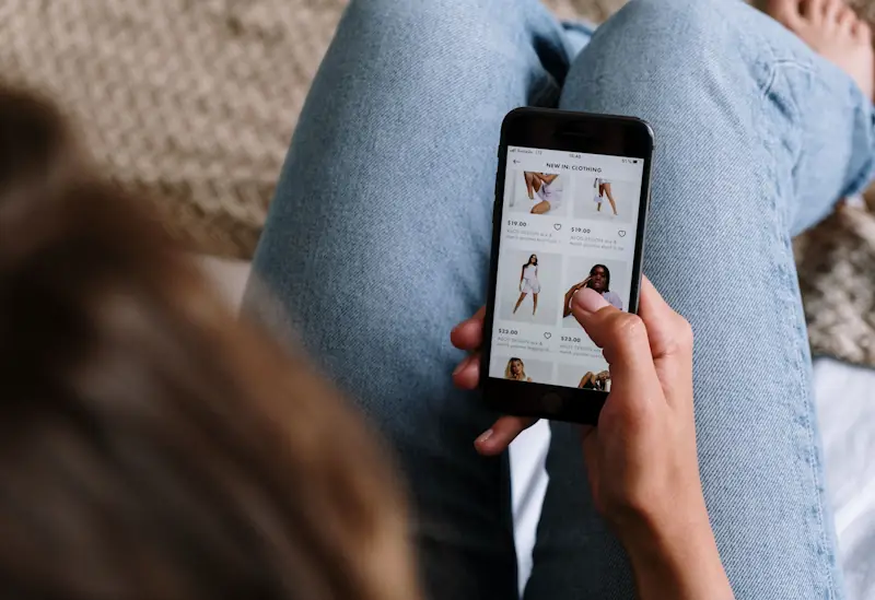 Person browsing clothing on a smartphone, representing how to shop smarter without buying less.