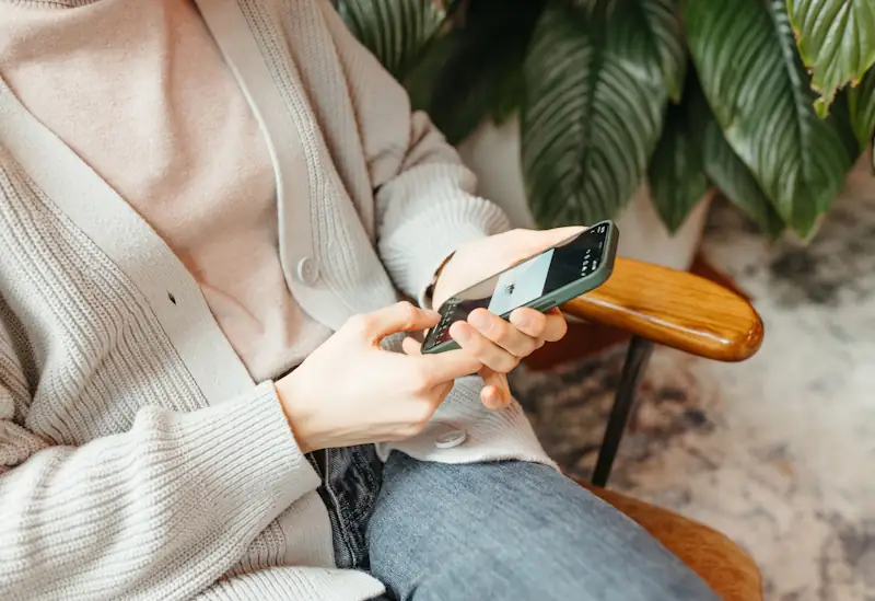 Person checking their smartphone, representing how to stop paying more than you need to on everyday costs.