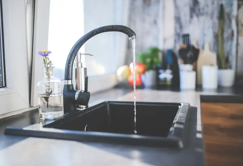 Water running from a kitchen tap with household items nearby